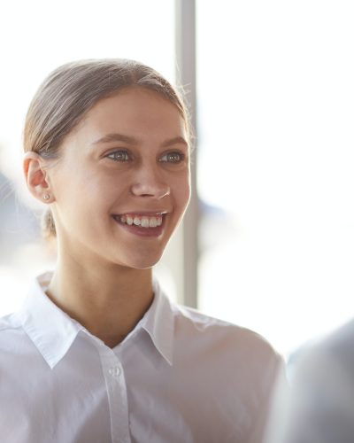 Smiling young lady talking to colleague
